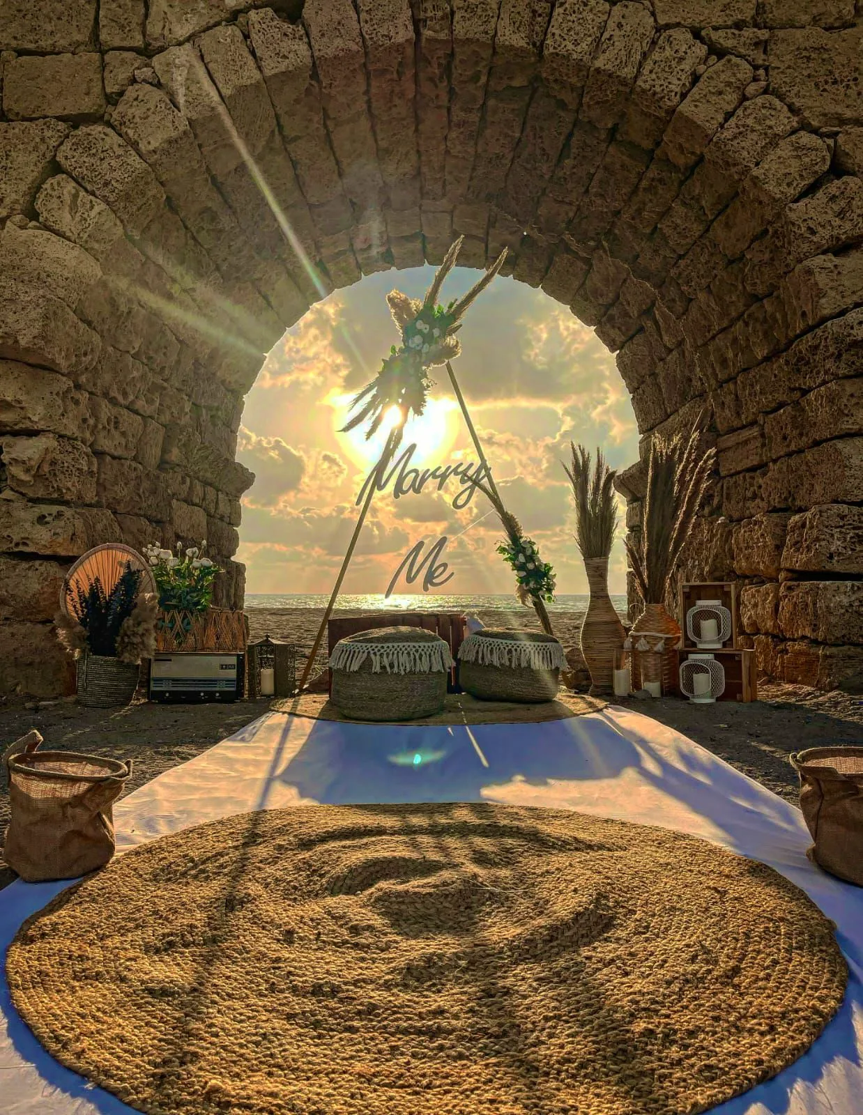 הצעות נישואין בעיצוב כפרי וייחודי, הכוללות עמדת צילום מרהיבה, שלט בכיתוב "marry me" , זרי פמפס בשילוב פרחים , שטיחי בוהו ואביזרי נוי תואמים ליצירת האווירה המושלמת !