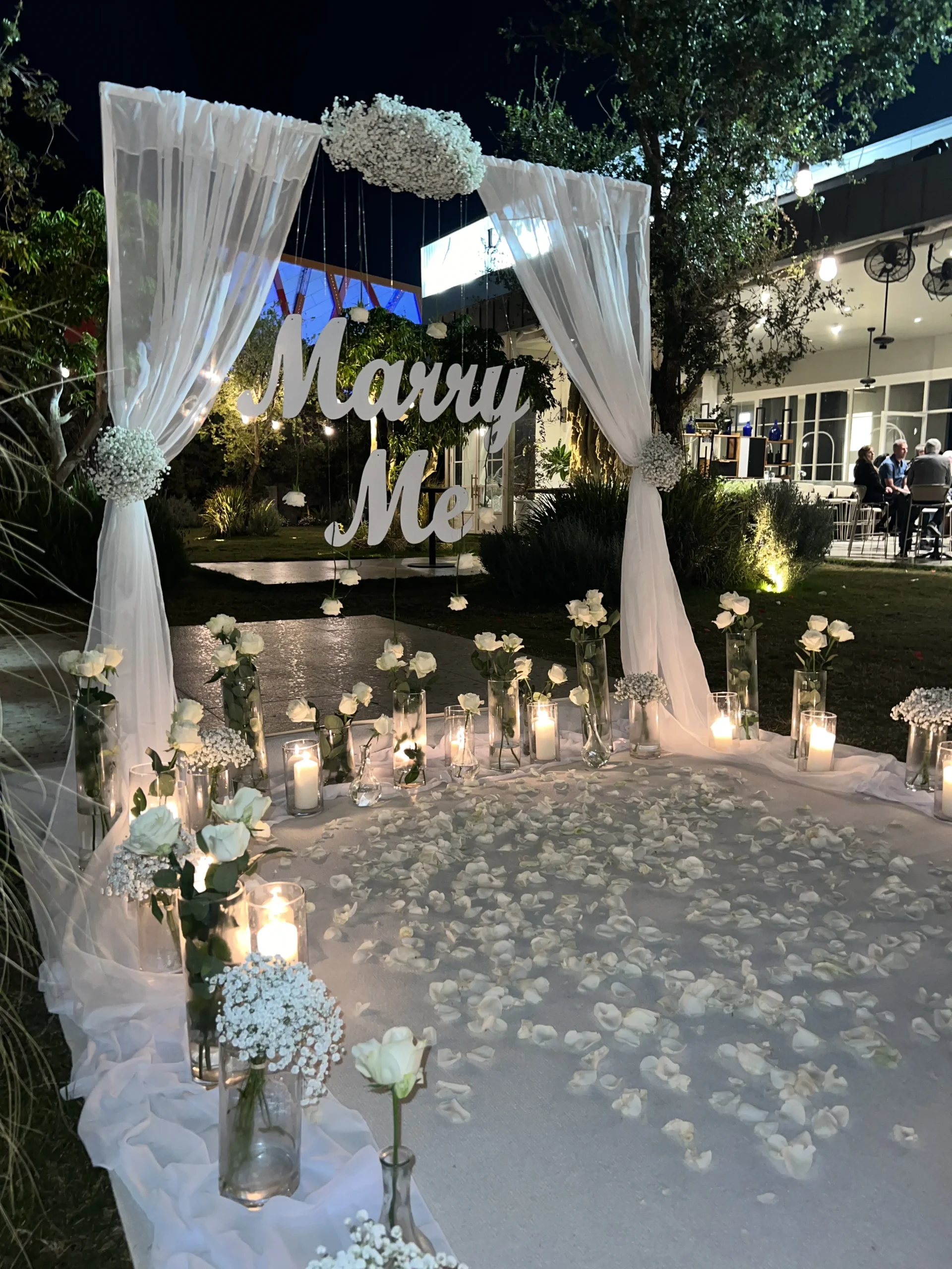 הצעת נישואין מהפנטת שמרגישה כמו חלום ! ההצעה נבנתה בדייקנות ובאהבה – שביל רחב ומרשים עטוף בעשרות זרי גיבסניות , ורדים טריים, נרות מעוצבים ובדי שיפון עדינים, המובילים לעמדה ייחודית דמוית חופה מעוטרת בזרי גיבסניות טריות, בדים וכיתוב "marry me". עיצוב עשיר, מדויק ובלתי נשכח.