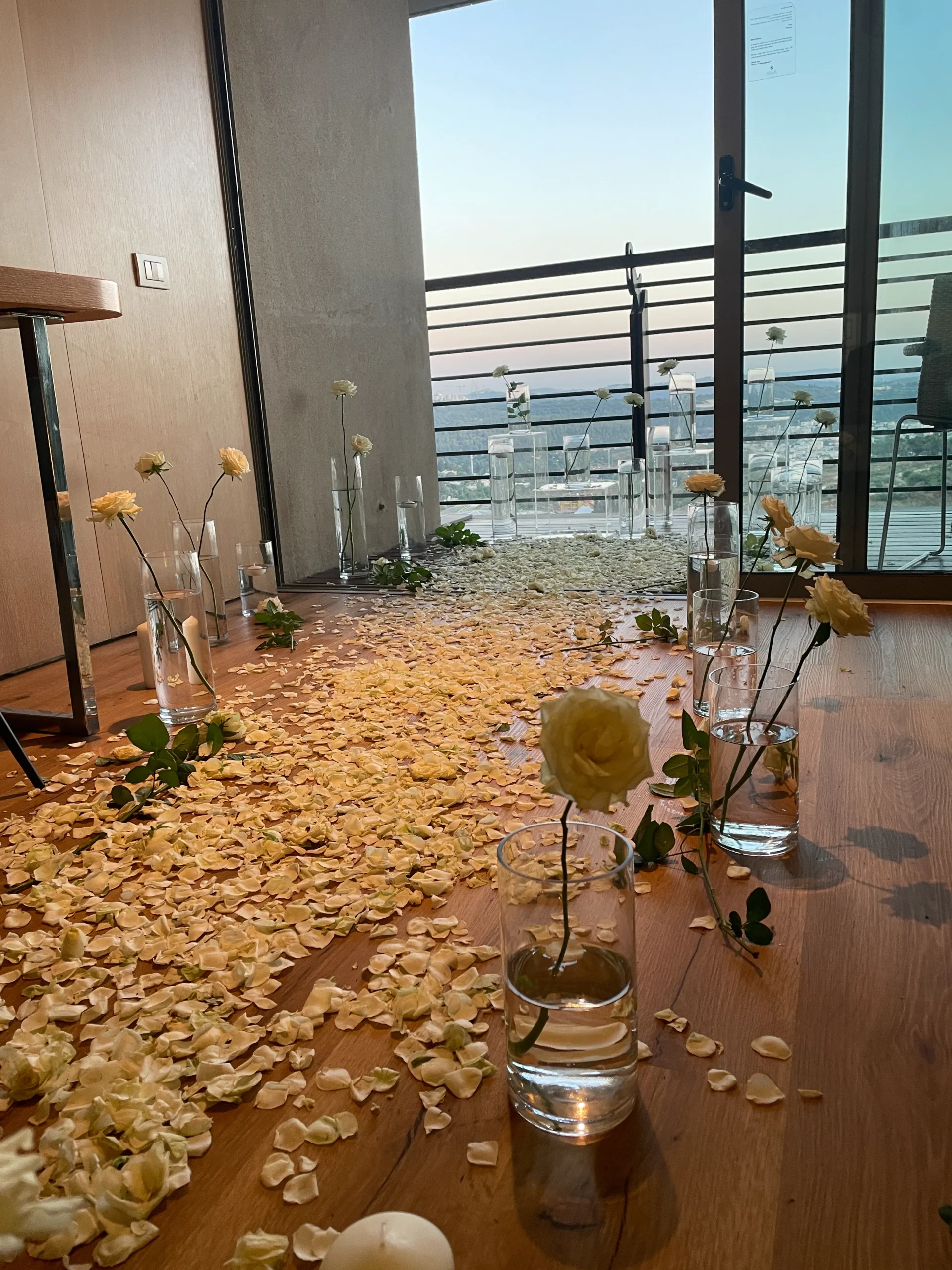 סידור שביל מרשים וייחודי להצעת נישואין, הכוללת וואזות זכוכית יוקרתיות, וורדים טריים , עלי כותרת ומעמדים שקופים בגבהים ליצירת אווירה מיוחדת ויוקרתית. מושלם להצעת נישואין אינטימית בבית מלון\ בבית.