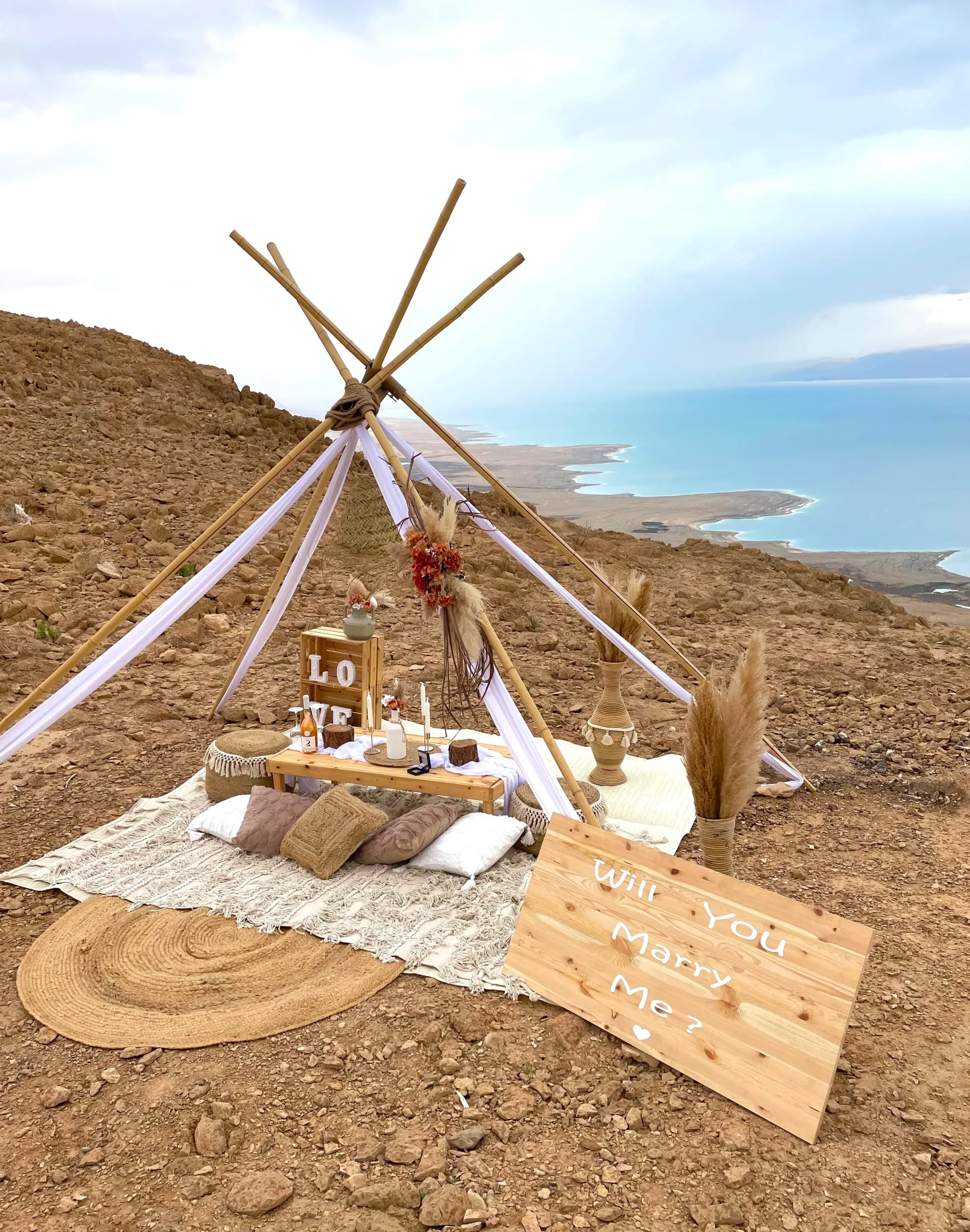 הצעת נישואין בעיצוב כפרי יוקרתי המשלבת עמדת במבוק עם בדים, זרי פמפס ופרחים ייבשים, שטיחים ואגרטלים תואמים. בנוסף פינת ישיבה מלאה הכוללת שולחן רביצה, פופים וכריות תואמים , ואביזרי נוי משלימים. עיצוב מושלם להצעת נישואין באווירה חמימה, מפנקת וקסומה !