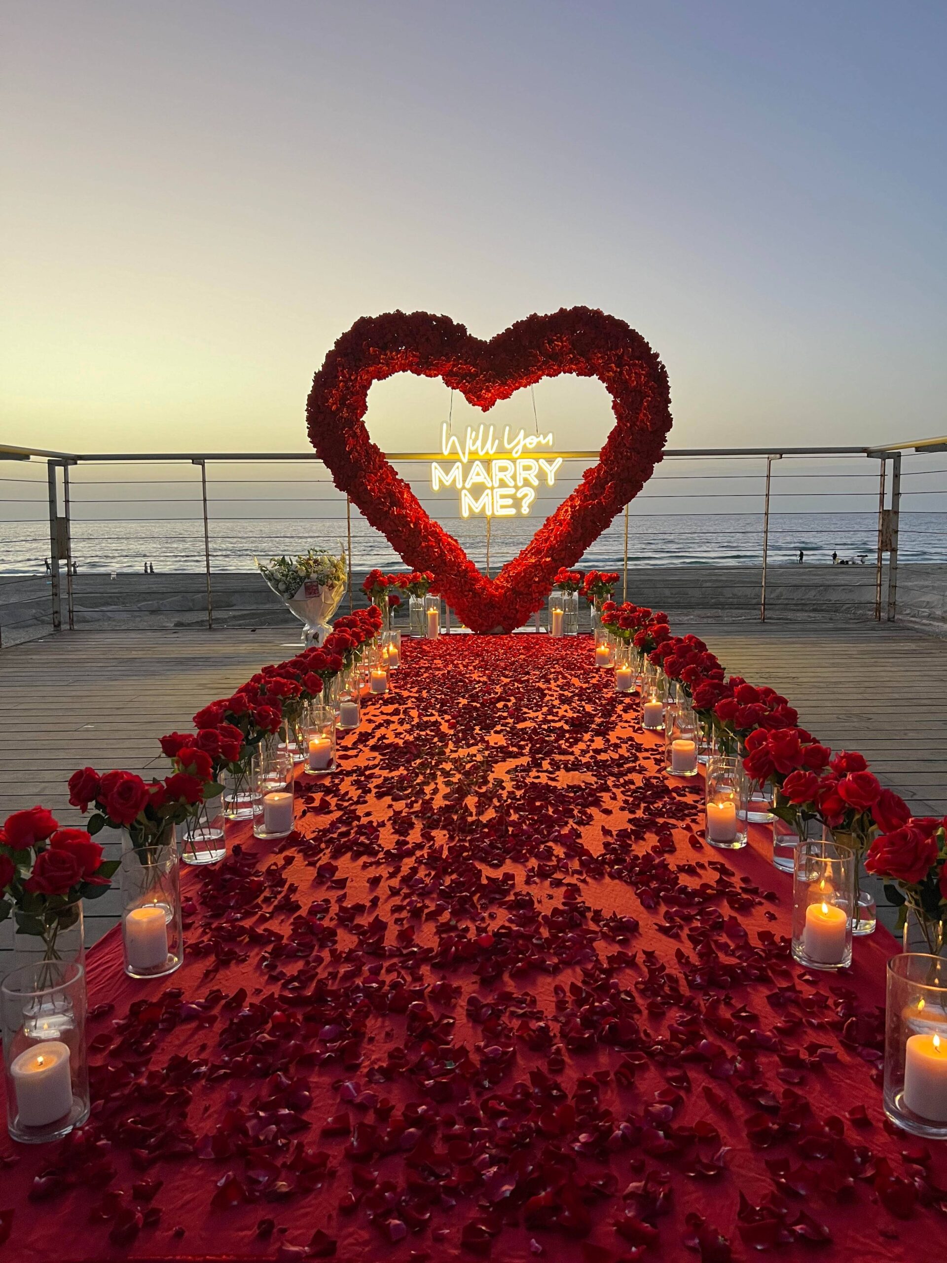 הצעת נישואין בעיצוב שביל לבן, זרי פרחים יוקרתיים ונרות, המובילים לעמדת לב עוצרת נשימה , עם שילוט בכיתוב "will you marry me?". שילוב של אלגנטיות, רגש ונוכחות בלתי נשכחת !