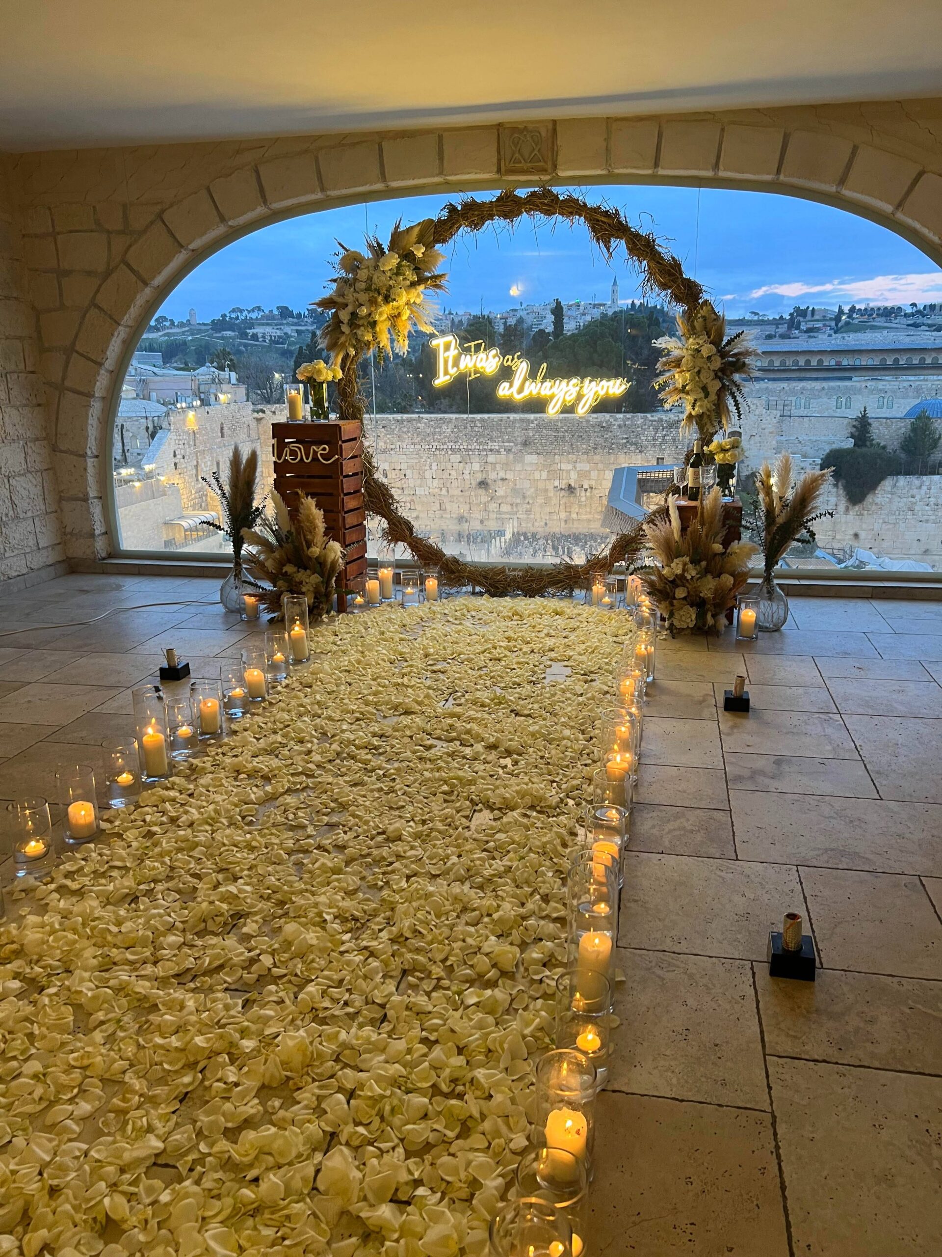 הצעת נישואין חלומית המשלבת מאות ורדים אמיתיים, נרות, וואזות זכוכית וזוג צועד על שביל של אהבה. עמדת עיגול בוהו עם זרי פרחים מרהיבים העשויים עבודת יד ושלט מואר וייחודי בכיתוב "It was always you" – לרגע אחד שהוא לנצח.