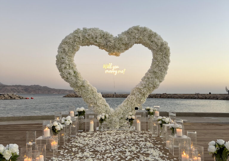 הצעת נישואין קלאסית ורומנטית המשלבת עיצוב מוקפד וייחודי וורדים חיים ליצירת האווירה המושלמת - מעמד בצורת לב ייחודי , שלט לד בכיתוב "will you marry me?" , וואזות , נרות ופרחים. עיצוב מושלם לחללים אינטימיים ומרווחים כאחד.