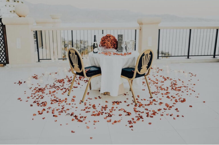 עיצוב שולחן באווירה רומנטית וייחודית , מעוטר בזר פרחים , בקבור יין וכוסות, עריכת שולחן , עלי כותרת מוורדים טריים ונרות להשלמת האווירה.