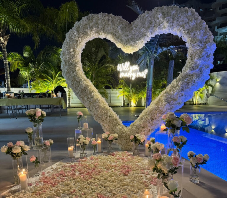 הצעת נישואין קלאסית ורומנטית המשלבת עיצוב מוקפד וייחודי וורדים חיים ליצירת האווירה המושלמת - מעמד בצורת לב ייחודי , שלט לד בכיתוב "will you marry me?" , וואזות , נרות ,פרחים ושביל בד תואם.