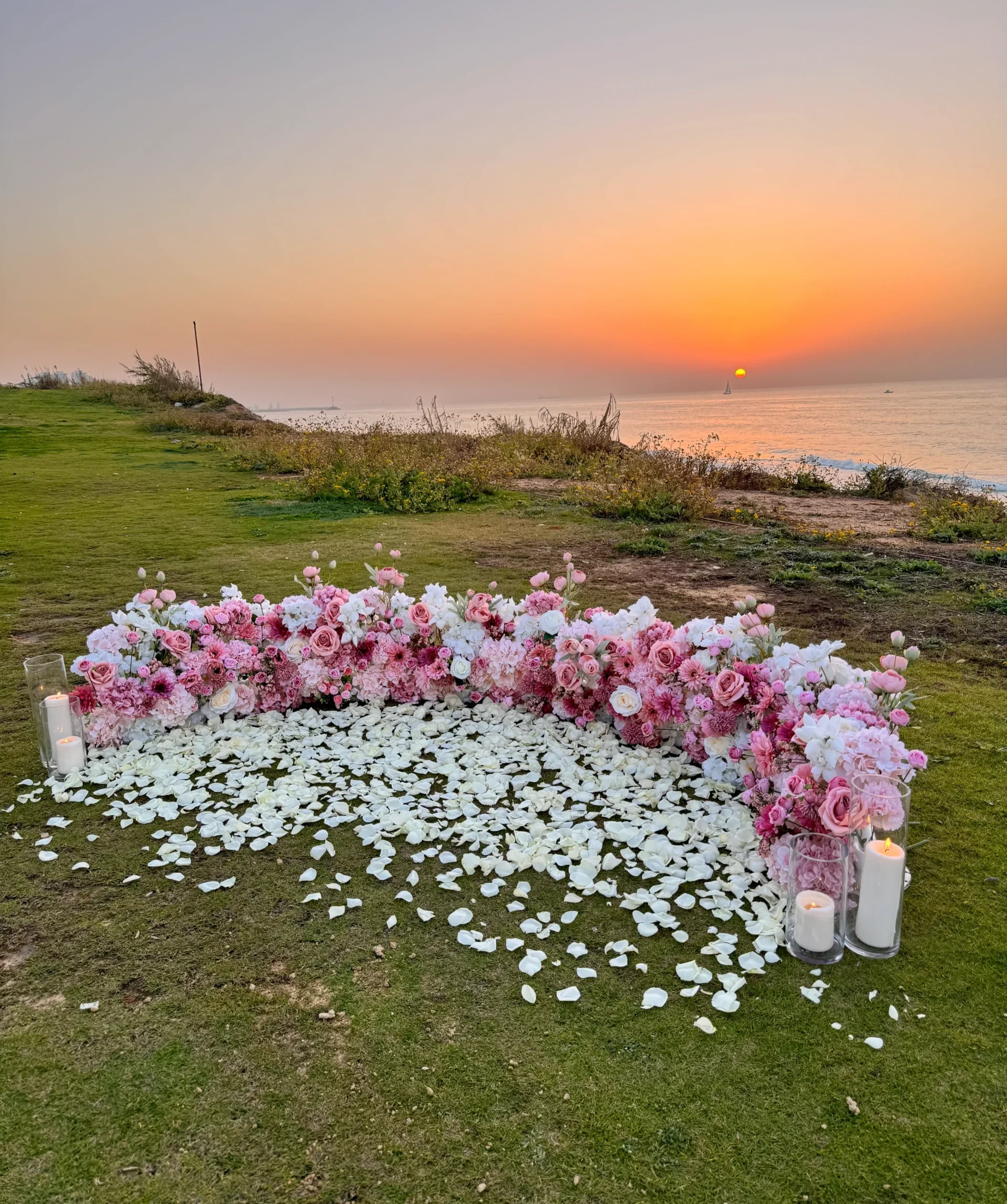 עיצוב הצעות נישואין באווירה טבעית ויוקרתית' המשלב תכנון מוקפד עם שזירת פרחים בצורה ייחודית, נרות ועלי כותרת טבעיים, הנותנים תחושת רוך טבעית ויוקרתית מול הנוף.